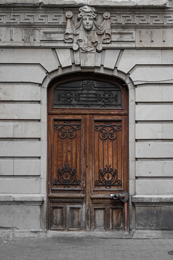 Weathered wooden door of an old building with a sculpture on top