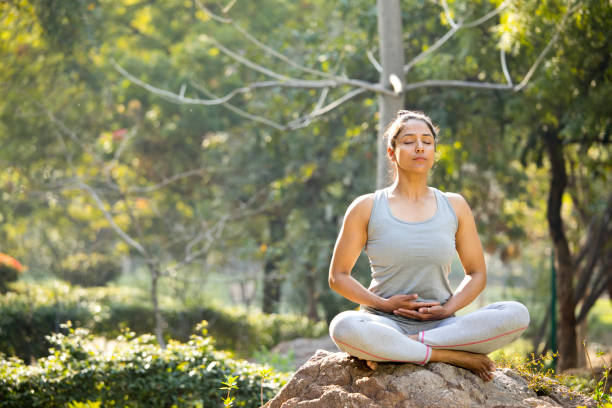 istock Woman practicing yoga in lotus position at park 1219397938