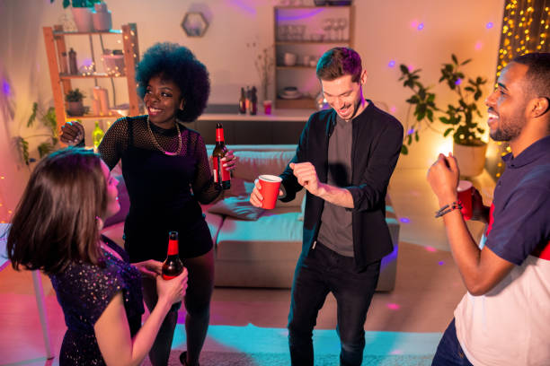 istock Young ecstatic intercultural friends with drinks dancing at home party 1219399411