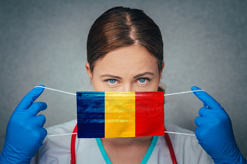 Coronavirus in Romania Female Doctor Portrait hold protect Face surgical medical mask with Romania National Flag. Illness, Virus Covid-19 in Romania, concept photo