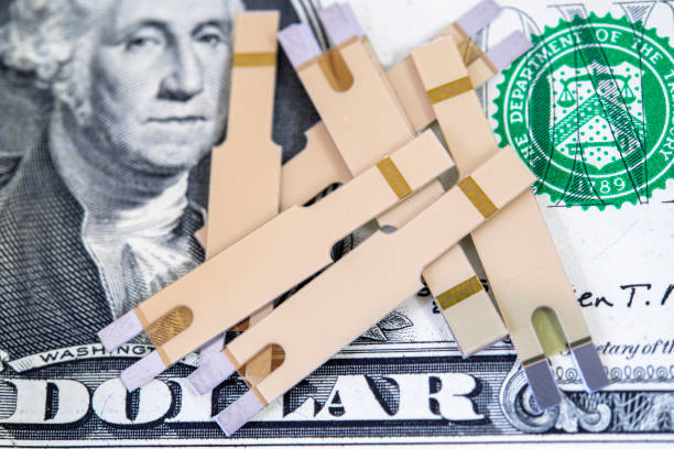 The cost of diabetes, testing strips over a one dollar bill, conceptual image