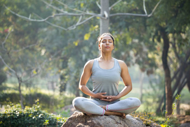 istock Woman practicing yoga in lotus position at park 1219401104