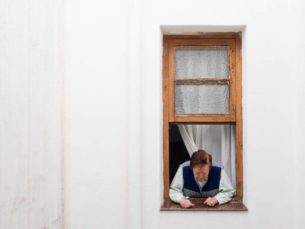 istock A senior woman peeps through window 1219401134