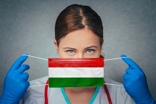 Coronavirus in Hungary Female Doctor Portrait hold protect Face surgical medical mask with Hungary National Flag. Illness, Virus Covid-19 in Hungary, concept photo