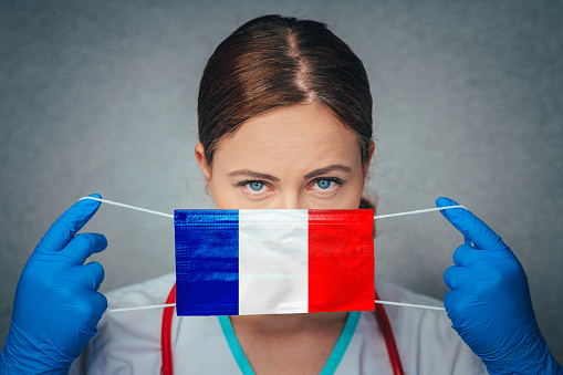 Coronavirus en Francia. La doctora mujer Retrato sostiene proteger la máscara médica quirúrgica de la cara con la bandera nacional de Francia. Enfermedad, Virus Covid-19 en Francia, foto conceptual photo