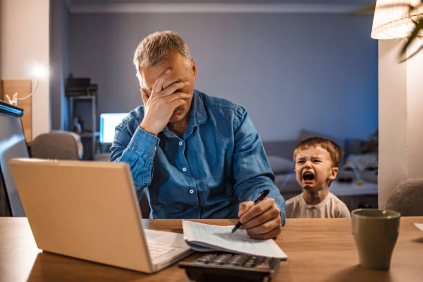 自宅で働く彼の2歳の息子とストレスの男 - コワークスペース ストックフォトと画像