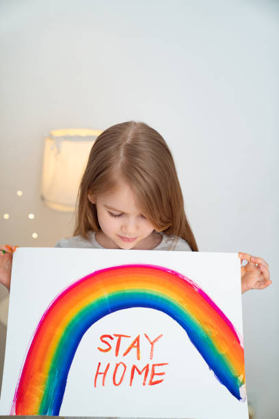 istock kid drew rainbow and poster stay home. 1219402973