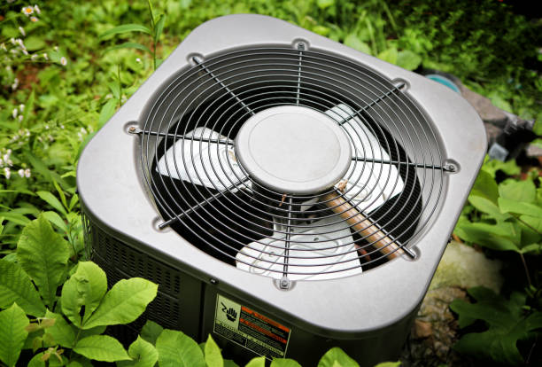 AC in growing greens Modern Air conditioner in grown greenery on background,  top view with warning sign for safety. air conditioner photos stock pictures, royalty-free photos & images