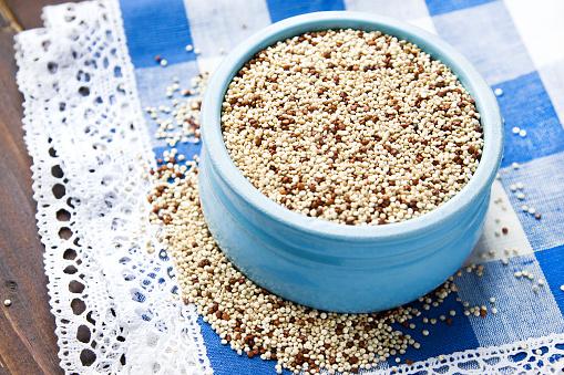 Organic quinoa grains in blue ceramic bowl, Gluten free. Concept Healthy food. Diet. Seeds of Chenopodium quinoa