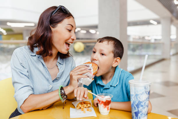 mor och hennes son med en snabbmat lunch tillsammans på mall - cafe buns eating bildbanksfoton och bilder