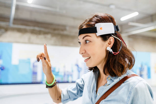 mujer con sensor de auriculares digital conectado a su oído, leer impulsos cerebrales - ordenador para utilizar como accesorio fotografías e imágenes de stock