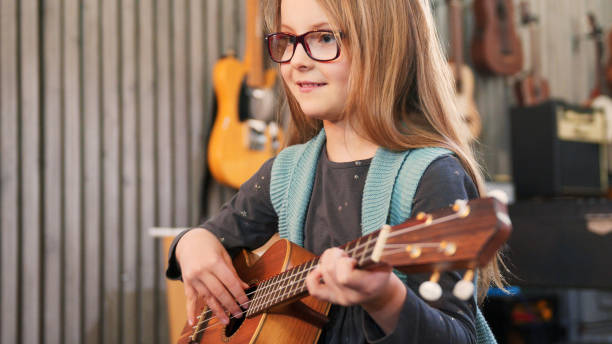 tata uczy gitary i ukulele do swojej córki. dziewczynka uczy się gry na gitarze w domu. z bliska. ukulele klasy w domu. dziecko uczy się gitary od ojca - skill piano music child zdjęcia i obrazy z banku zdjęć