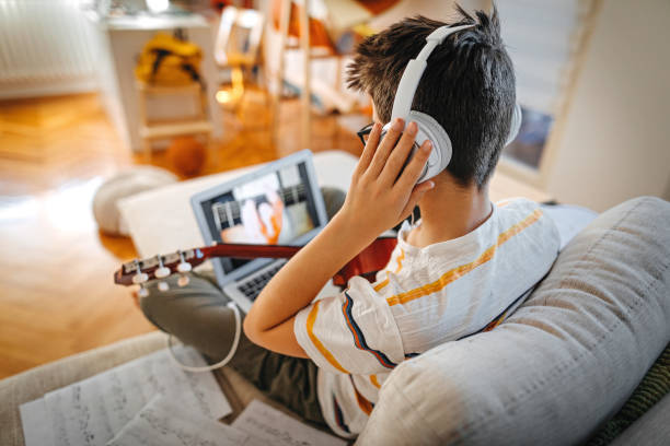 teenage boy watching online guitar lessons - number 12 audio imagens e fotografias de stock