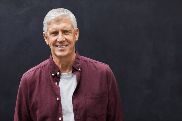 istock Smiling mature man standing against wall 1219408090