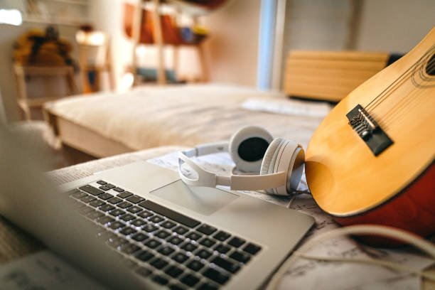 Close-up of laptop, headphones and guitar on a couch at home