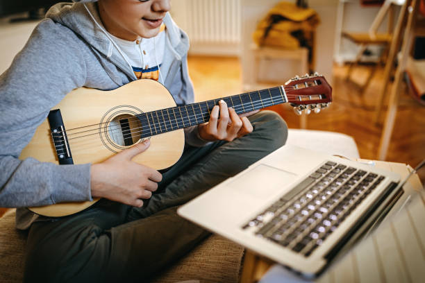 istock Teenage boy learning to play guitar watching online tutorial 1219408877