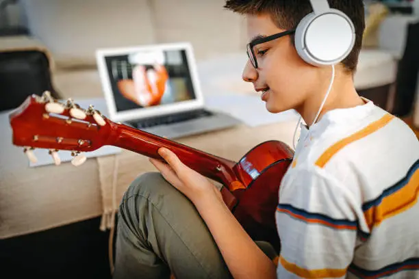 Photo of Teenage boy having online guitar lesson