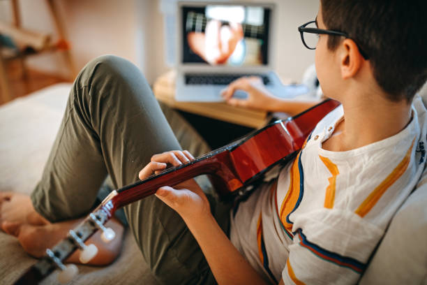 istock Teenage boy watching online guitar lessons 1219409120