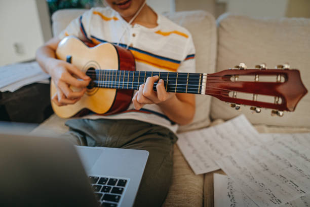 istock Teenage boy learning to play guitar watching online tutorial 1219409176