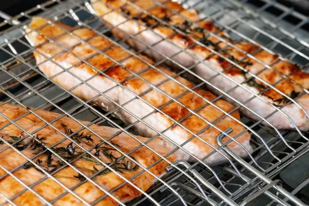 Photo of Top view grilled salmon on grid over open flame. A few slices of barbecue fish fillet. Keto diet food. Selective focus.