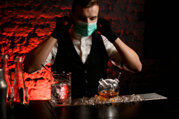 istock bartender in mask with black gloves drink preparing to make cocktail in special flask 1219410351