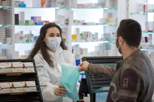 una farmacéutica que lleva una mascarilla quirúrgica da medicamentos al paciente - medical exam dental hygiene caucasian mask fotografías e imágenes de stock