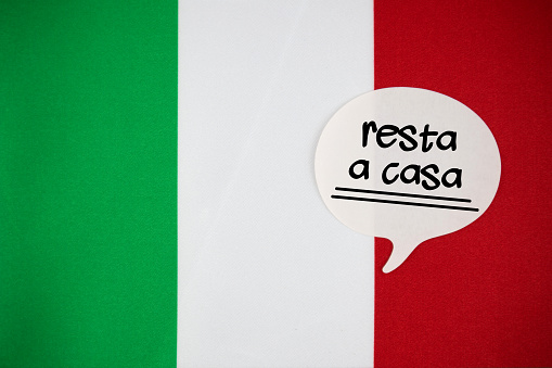White Speech Bubble Note Paper With Stay Home Message in Italian Language On The Italian Flag. Horizontal composition with copy space.