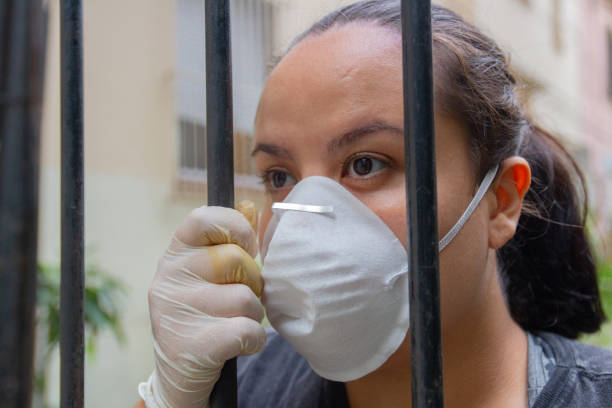 istock white woman with mask and glove behind a grid during coronavirus quarantine 1219420397