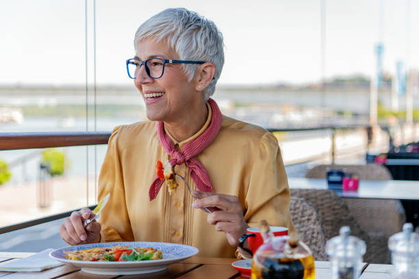 счастливая старшая женщина, наслаждающаяся обедом в ресторане. - smart casual occupation casual healthy eating стоковые фото и изображения