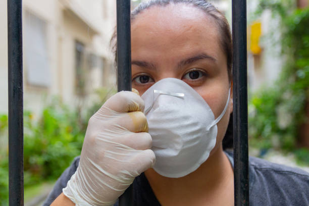 istock white woman with mask and glove behind a grid during coronavirus quarantine 1219420635