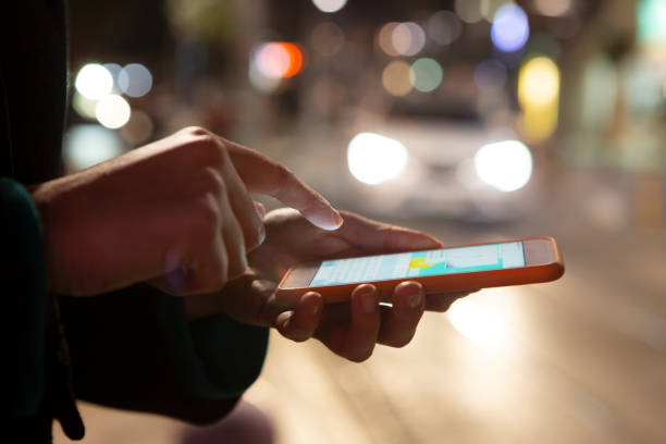 istock Woman using her mobile phone, city skyline night light background 1219422117