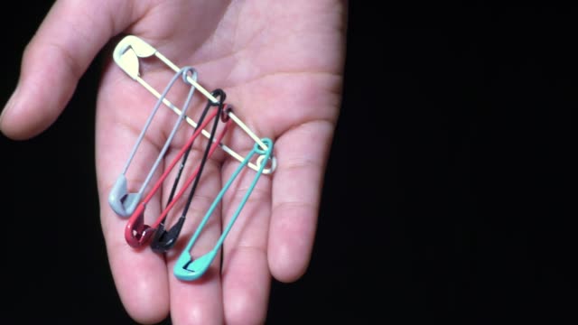 A woman shows safety pins of many colors in hand
