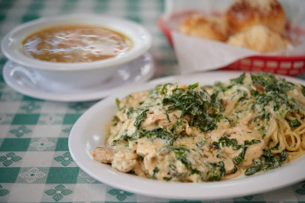 Spinach chicken pasta white sauce with garlic rolls and soup on the table stock photo