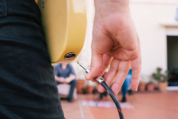 Detail of the plug into the musical instrument before an intimate concert. Close up of a male hand unplugging a music wire to an electric guitar. Leisure , free time , entertainment and music industry amplifier plug stock pictures, royalty-free photos & images