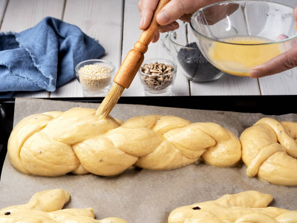 Easter pastries, challah, rabbit-shaped buns. Proofing baking before placing in the oven. Brush brush with butter buns before baking. Close-up. Braided sweet bread dough.