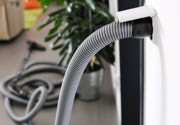 Central vacuum cleaner hose plugged in to wall inlet stock photo