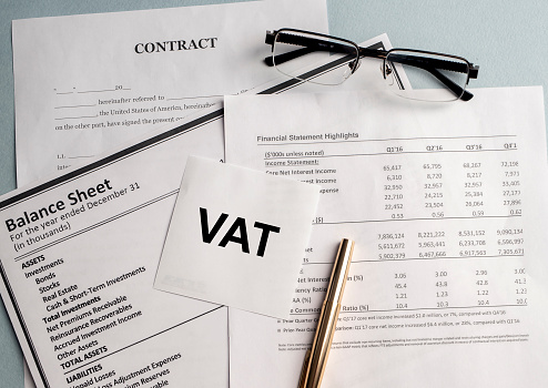 Word VAT on sticker with pen glasses on documents. Tax time. Tax payment deadline.