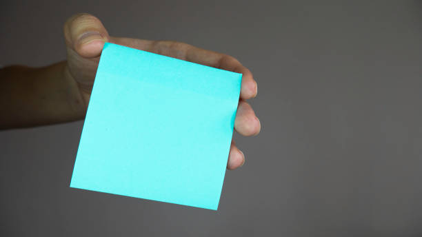 istock Square paper with space for text in the hand. Sticky note with in a hand. 1219430204