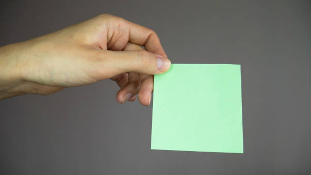 istock Hand holding a blank sticker. Square paper with space for text in the hand. Sticky note with in a hand. 1219430208