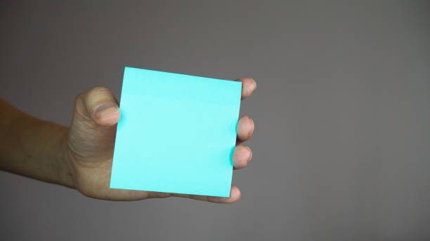 istock Square paper with space for text in the hand. Sticky note with in a hand. 1219430215