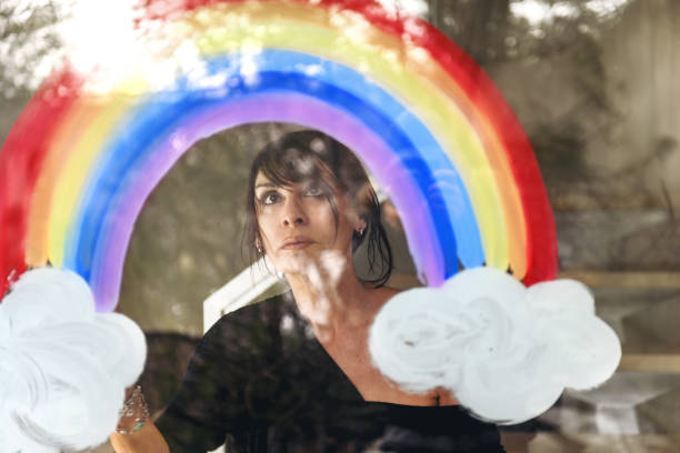 istock Woman painting a rainbow on a window 1219430844