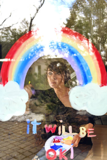 istock Woman painting a rainbow on a window 1219430845