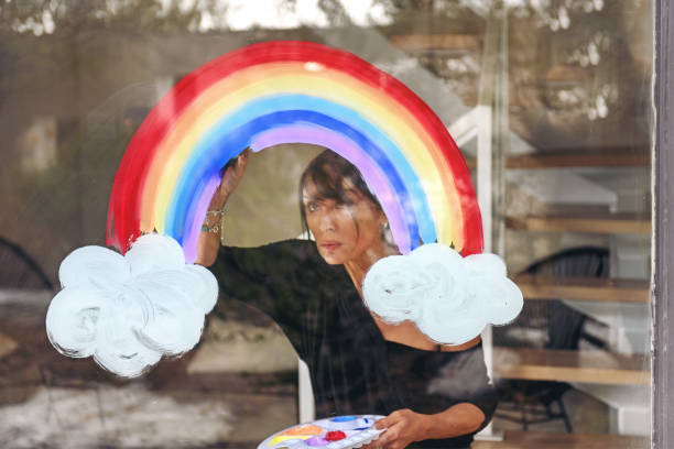 istock Woman painting a rainbow on a window 1219430869