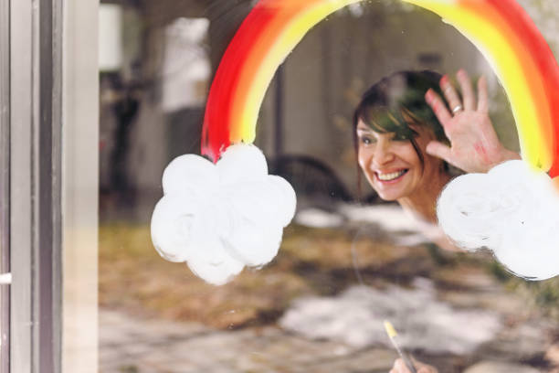 Woman photographed through window, painting a rainbow, It will be ok, quebec, Canada