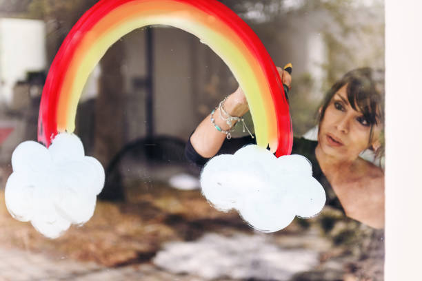 istock Woman painting a rainbow on a window 1219430927