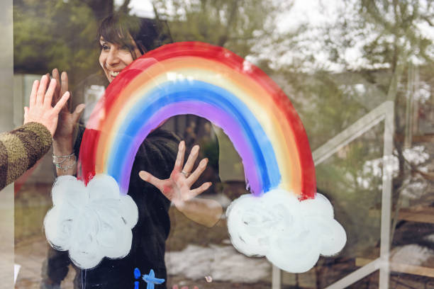istock Woman painting a rainbow on a window 1219430929