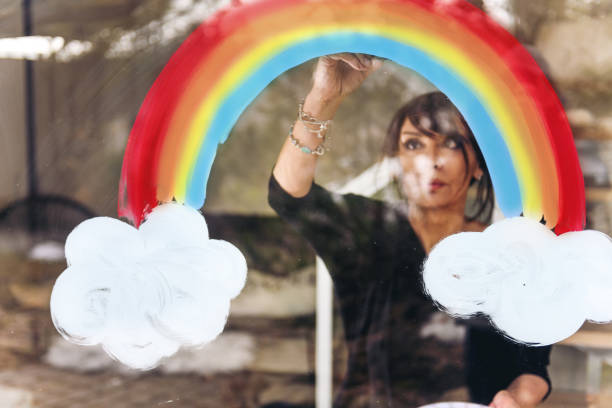 istock Woman painting a rainbow on a window 1219430965