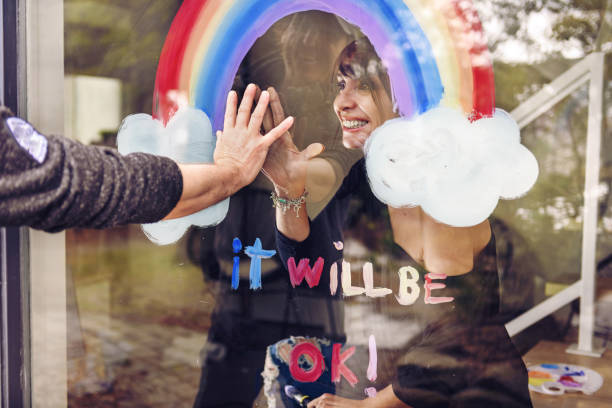 Woman painting a rainbow on a window