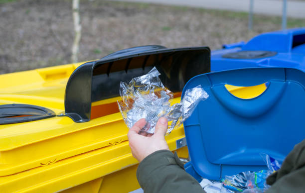 istock Person (man's hand only in the picture) is sorting garbage from his trash bean near the recycling containers and puts some piece of plastic to yellow container for plastics. 1219432200