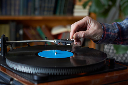 Male hand placing the needle on record plate, selective focus